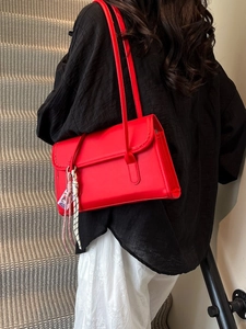 Classic red baguette shoulder bag in matte faux leather worn by a model on stairs