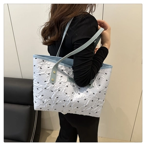Dettaglio borsa tote blu con motivi a fiocco nero ed etichetta in pelle trendy