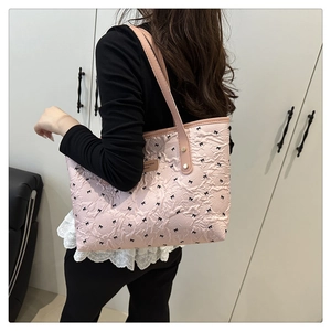 Borsa tote rosa con fiocchi, texture stropicciata e manici in pelle indossata a spalla