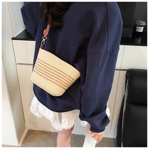 Vue détaillée du sac seau en paille tressée avec bandoulière en cuir et rayures
