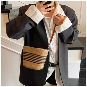 Détail du sac seau en paille tressée à rayures noires et fine bandoulière cuir