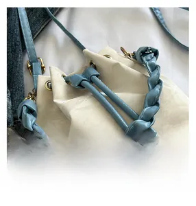 Detail view of woven blue handles and drawstring on a cream leather bucket bag