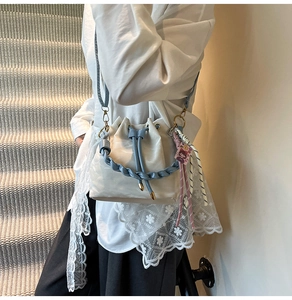Model wearing a creamy white leather bucket bag with blue woven handle and shoulder strap
