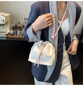 Detail of white pleated bucket bag with pink braided handle and drawstring closure