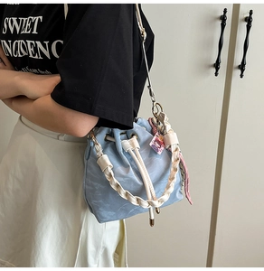 Detail of light blue bucket bag with drawstring closure and white woven handle