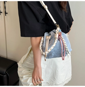 Light blue drawstring bucket bag with woven handle and charm detail shown on model