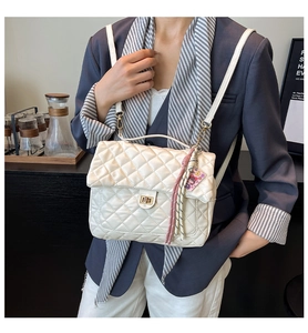 Detail of quilted backpack with golden twist lock and stylish pink woven charm