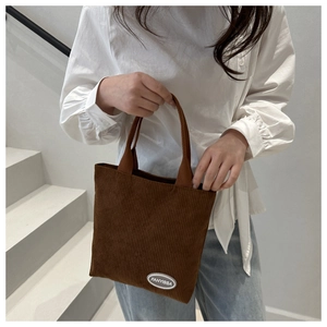 Detail of vintage brown corduroy tote bag showing soft texture and logo on white stairs