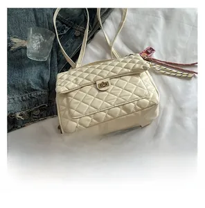 Flat lay of cream quilted rhombic backpack with gold metal clasp on white bedding