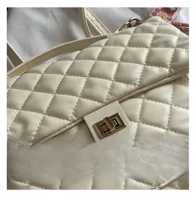 Close-up of cream quilted diamond pattern and golden twist lock on the leather backpack
