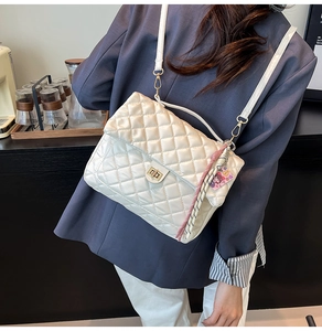 Detailed view of white quilted faux leather bag featuring a gold rotary metal lock buckle