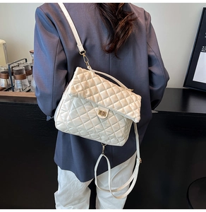 Detail of white quilted tote bag featuring golden turn-lock closure and shoulder strap