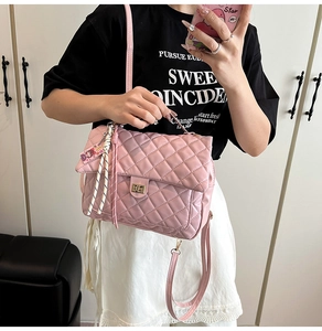 Detailed shot of pink quilted backpack with gold turn-lock and decorative cartoon pendant