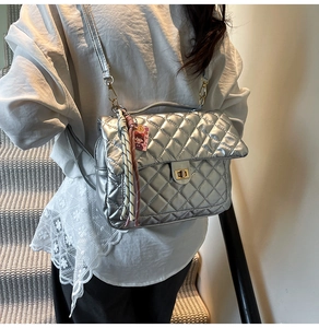 Detail of silver quilted texture backpack with gold twist lock and colorful tassel charm