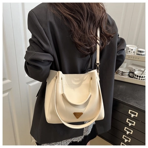 Close-up of cream white bucket bag with gold triangle logo and premium leather texture