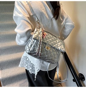 Detail of silver quilted backpack with gold twist lock and striped scarf accessory