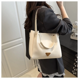 Close-up of white leather tote bag with gold triangle logo and versatile straps