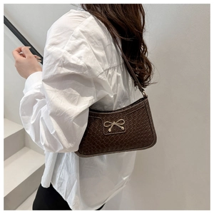 Detail of coffee brown woven texture shoulder bag with metallic bow charm detail
