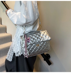 Detailed view of silver quilted crossbody bag with metal twist lock and chain strap