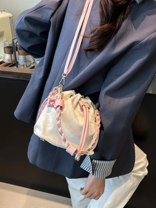Fashionable drawcord bucket bag with woven handle and pink shoulder strap for women