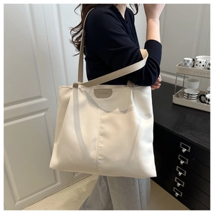 Detailed shoulder view of a large cream nylon tote bag with reinforced brown handles
