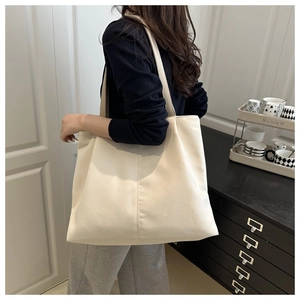 Close-up of off-white lychee texture tote bag worn on shoulder for daily commute