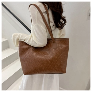 Detailed view of brown woven texture and brand patch on stylish PU leather tote bag
