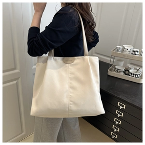 Detail of a minimalist beige nylon tote bag showing vertical seam and fashion label