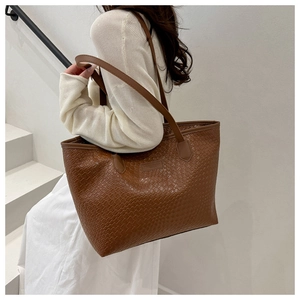 Close-up of dark brown woven texture tote bag with long leather shoulder strap detail