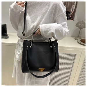 Détail du sac cabas rétro noir avec ferrures dorées et plaque métallique triangulaire