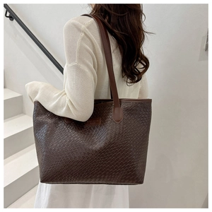 Detail of dark brown woven leather tote bag with brand logo and square texture