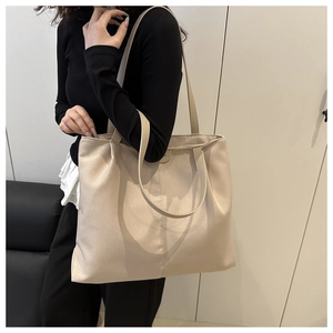 Side view of large beige faux leather tote bag showing drape and capacity on a model