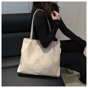 Close-up of beige oversized suede tote bag with vertical stitching and slim straps
