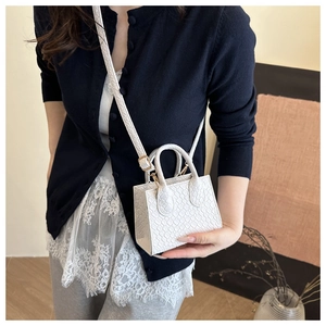 White mini crossbody bag with crocodile texture shown on model for size perspective