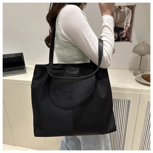 Macro detail of the black tote bag texture with fashion label and leather shoulder strap