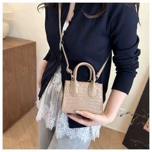 Detail of beige woven texture mini handbag with slender shoulder strap on a model