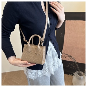 Detail of khaki crocodile embossed mini crossbody bag with top handle and fine shoulder strap