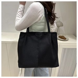 Close-up of black canvas tote bag worn on shoulder, stylish large capacity design