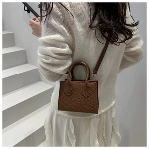 Brown woven texture handbag styled with a white outfit on a minimalist staircase