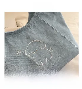 Detailed view of light blue canvas tote with embroidered puppy and winter stories text