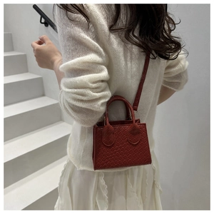Deep red woven texture mini tote bag shown on model against a white minimalist backdrop
