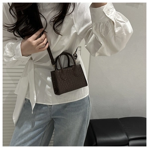 Brown crocodile-embossed crossbody bag shown on a model in a minimalist home setting