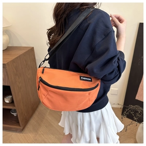 Detail view of the durable nylon fabric and fashion label on the orange crossbody saddle bag