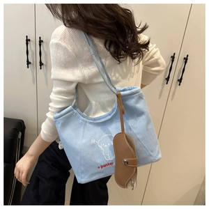 Detail view of light blue denim tote bag with white puppy embroidery and leather case