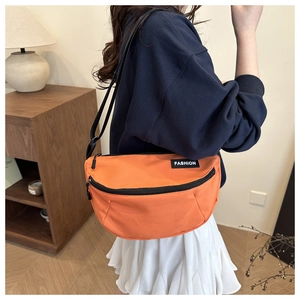 Close-up of orange water-resistant crescent bag with adjustable strap on a model