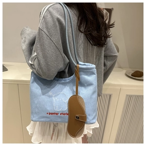 Detail of light blue denim tote with cute puppy embroidery and brown leather accessory