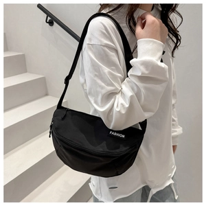 Détail d'un sac bandoulière noir en nylon avec sangle réglable et étiquette de mode