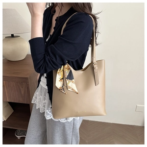 Detailed close-up of khaki leather tote bag with elegant geometric printed silk scarf handle