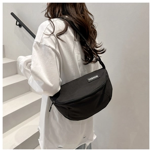 Close-up of black crossbody bag featuring a FASHION label and adjustable nylon strap