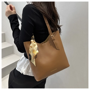 Detail of caramel leather tote bag with printed silk scarf and fashion logo on side